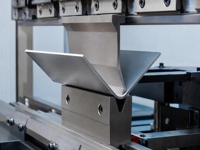 CNC press brake operator inspecting inside bend radius of stainless steel sheet metal enclosure